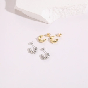 Détail de boucles d'oreilles opale en forme de C en or et argent avec finition texturée