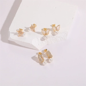 Detailed view of 14K gold butterfly earrings with zircons, shells and white pearls