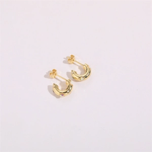 Détail de boucles d'oreilles créoles dorées en C avec incrustation de zircon coloré et strass
