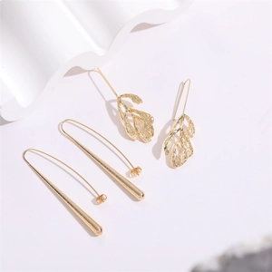 Detailed macro view of matte gold leaf earrings and sleek long cone pendants