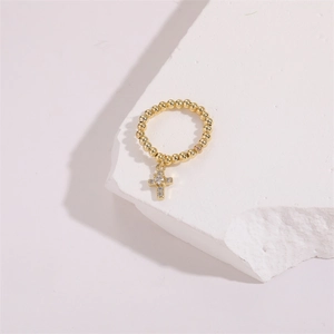 Macro shot of gold beaded ring with sparkling zircon cross pendant on a white rock