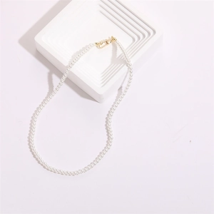 Collier élégant de perles blanches avec fermoir mousqueton doré sur support moderne