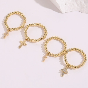 Macro shot of gold beaded rings with zircon-inlaid cross pendants on white stone