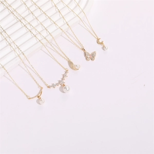 Close-up of gold necklaces with pearl pendants and zircon butterfly and moon designs