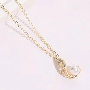 Detailed macro view of a gold-plated flower pendant featuring zircon stones and a white pearl