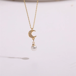 Detail of gold crescent moon pendant with sparkling zircon and white hanging pearl