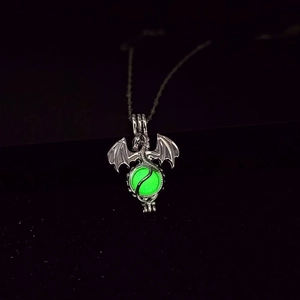 Detailed macro view of the glowing green orb held by the silver dragon pendant
