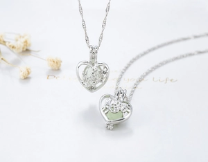 Detailed macro of hollow heart necklace with glowing green bead and I Love You engraving