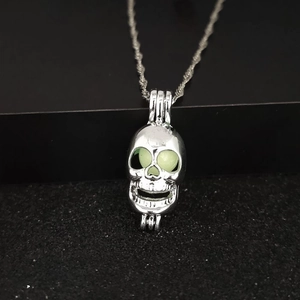 Gothic hollow skull pendant necklace with luminous green glowing eyes on black background