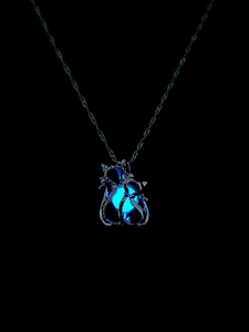 Leuchtende Doppelkatzen-Halskette mit blauem Glüheffekt vor dunklem Hintergrund