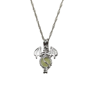 Macro detail of silver dragon pendant showing textured scales and green luminous stone