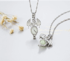 Detailed view of an openable hollow luminous dragon necklace pendant with a green bead