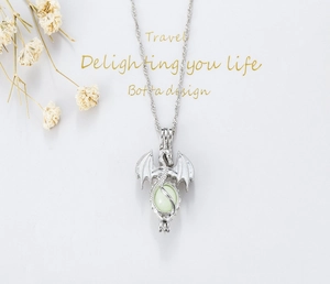 Detailed view of the luminous dragon pendant necklace with green bead and silver wings