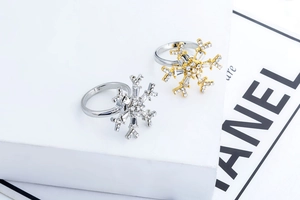 Detailed view of silver and gold snowflake rings with cubic zirconia on white stone