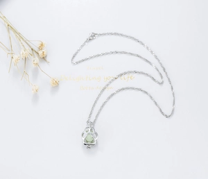 Detail of silver water wave chain necklace with hollow dog paw pendant and green bead