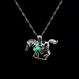 Glow-in-the-dark horse pendant necklace with luminous green bead on black background