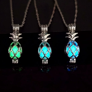 Luminous pineapple pendant necklaces in green, cyan, and blue glows on black background