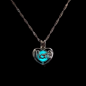 Macro shot of luminous heart pendant with Mom inscription glowing blue in the dark