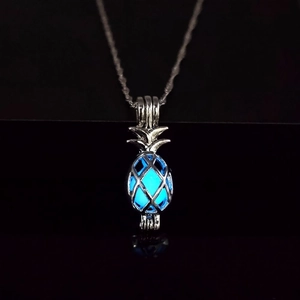Detail of hollow pineapple glow necklace with ice blue luminous stone in darkness