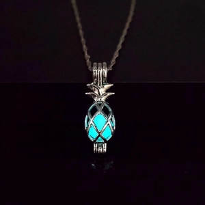 Close-up of a glowing hollow pineapple pendant with inner luminous stone on black background