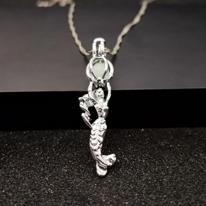Close-up of glowing mermaid pendant with clear scale textures on black pedestal