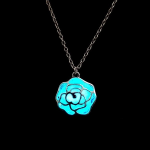 Leuchtende blaue Rose Anhänger Halskette mit hohlem Design in dunkler Umgebung