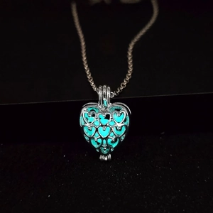 Détail du pendentif cœur évidé brillant d'une lumière bleu cyan dans l'obscurité
