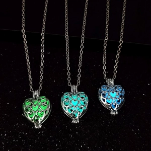 Trois pendentifs cœur évidés montrant des lueurs verte cyane et bleue dans le noir