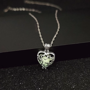 Luminous heart necklace with glowing elephant pendant in green light on black background