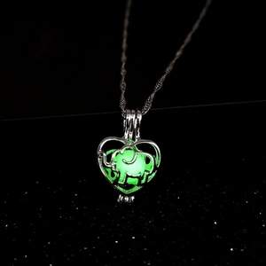 Luminous elephant heart pendant necklace with glowing green stone in dark background