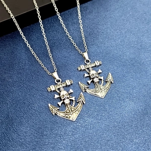Vue macro du collier ancre tête de mort lumineux sur fond de tissu bleu foncé élégant