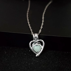 Macro view of luminous heart necklace with silver hollow frame and mint green stone