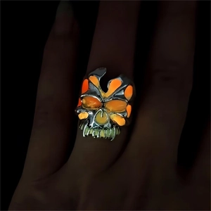 Nahaufnahme eines Punk-Totenkopfrings, der im Dunkeln hell orange und grün leuchtet