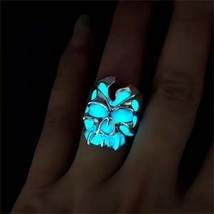Makroaufnahme von leuchtendem Totenkopf-Ring mit blauem Glühen im Dunkeln für Herren