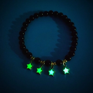 Leuchtende Sternanhänger an schwarzem Perlenarmband mit grüner Fluoreszenz im Dunkeln