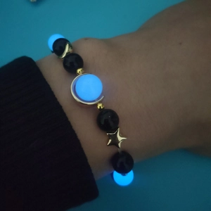 Close-up of star and moon beaded bracelet with blue glowing stones on model wrist