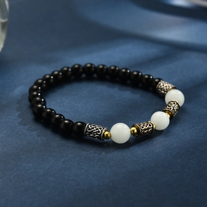 Détail des perles en obsidienne et agate blanche avec des entretoises en métal style celtique
