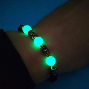 Gros plan de perles vertes lumineuses et d'entretoises en métal sur un bracelet brillant
