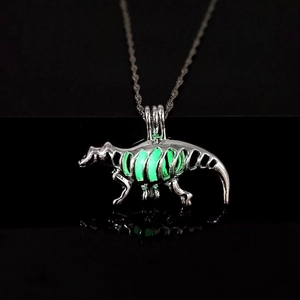 Macro shot of silver dinosaur skeleton pendant with vibrant green glow-in-the-dark feature