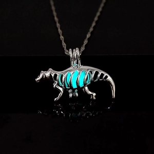 Detailed macro view of a luminous dinosaur skeleton pendant with a blue glow on black glass