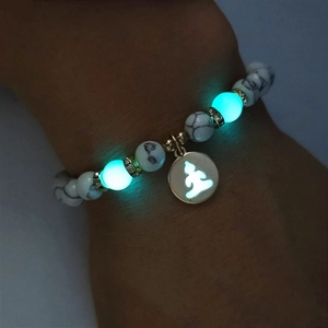 Leuchtendes Yoga-Armband mit Buddha-Anhänger am Handgelenk in dunkler Umgebung