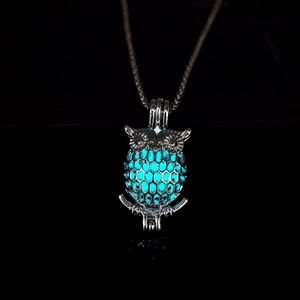 Detailed macro shot of the luminous owl pendant glowing in bright lake blue color