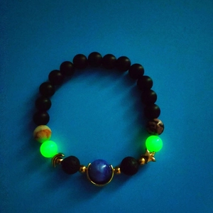 Detail of luminous beaded galaxy bracelet with blue planet bead and gold star charm