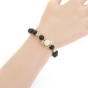 Luminous starry sky beaded bracelet with matte black beads and gold planet charm on a wrist