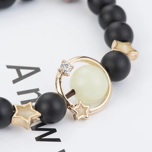 Macro shot of luminous beaded bracelet with star accents and gold pendant detail