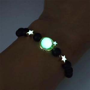 Luminous star and moon beaded bracelet glowing in the dark on wrist close-up