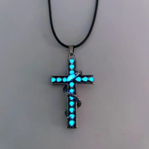 Detalle del colgante de cruz con corazón azul luminoso y serpiente en cordón negro