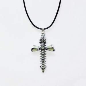 Detailed view of gothic skull and spine cross pendant with glowing green inlay