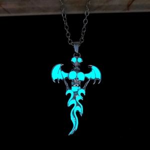 Gothic skull pendant with bat wings showing a bright blue luminous glow in the dark