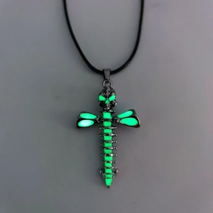 Detailed view of gothic cross and skull pendant glowing with green light effect